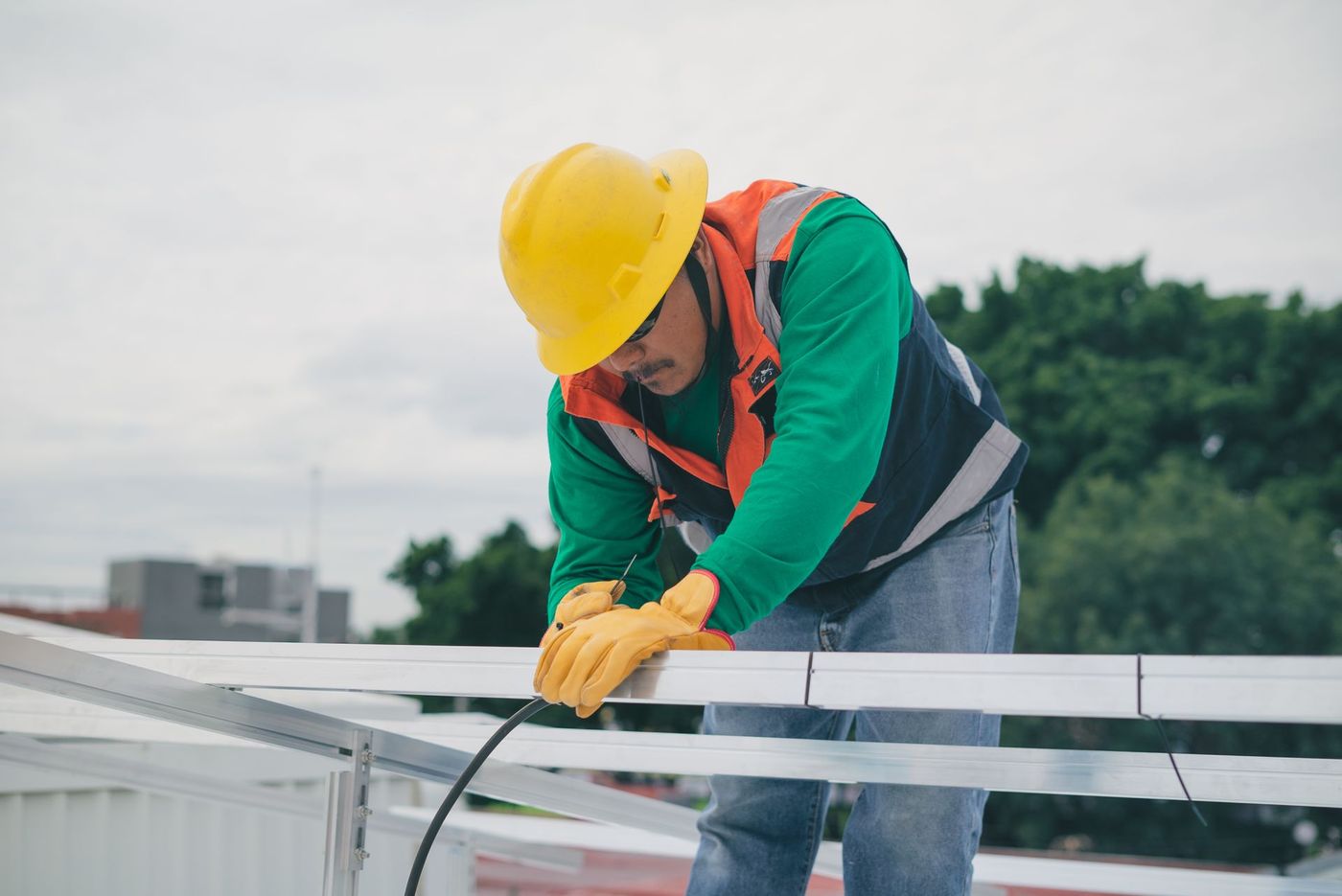 Technician wiring rooftop solar panel mounting rails